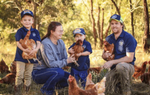The Watson family of Watson Family Produce, with their children, standing on their farm holding chickens.