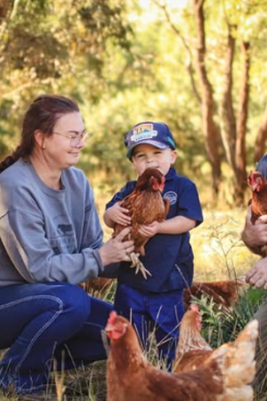 The Watson family of Watson Family Produce, with their children, standing on their farm holding chickens.