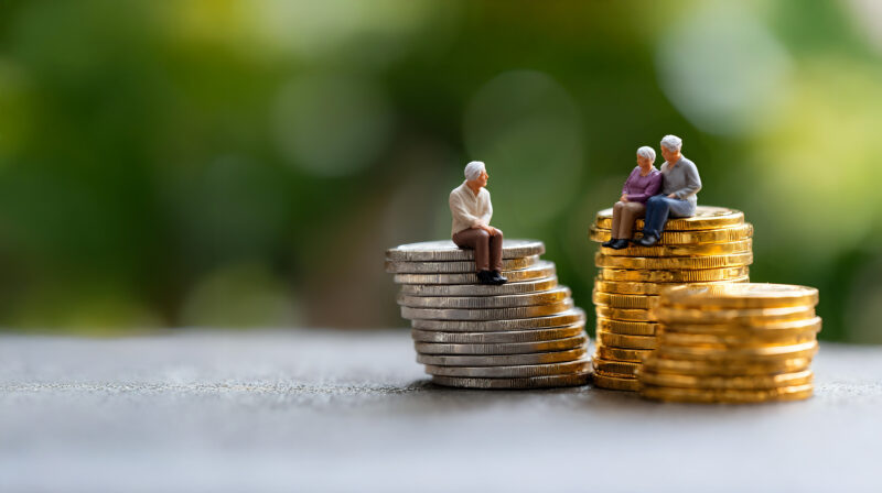 Miniature elderly figures sitting on coin stacks, symbolising retirement savings and financial security.