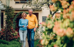 Retired couple walking in front yard of home