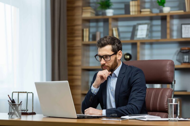 A business owner reviewing financial information on a laptop, considering the impact of interest rates on the value of their business.