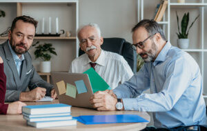 A multi-generational family group reviewing documents and notes on a laptop as they discuss proposed changes to discretionary trust taxation in Australia.