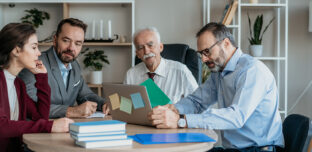 A multi-generational family group reviewing documents and notes on a laptop as they discuss proposed changes to discretionary trust taxation in Australia.