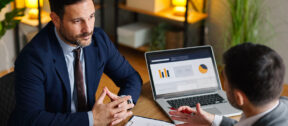 Two professionals discussing financial records and business documentation during a workplace meeting. The image reflects proactive tax governance, reporting review and compliance planning.