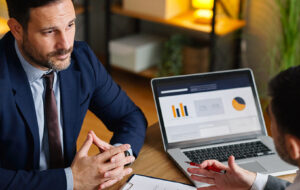 Two professionals discussing financial records and business documentation during a workplace meeting. The image reflects proactive tax governance, reporting review and compliance planning.