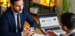 Two professionals discussing financial records and business documentation during a workplace meeting. The image reflects proactive tax governance, reporting review and compliance planning.