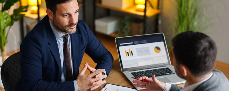 Two professionals discussing financial records and business documentation during a workplace meeting. The image reflects proactive tax governance, reporting review and compliance planning.